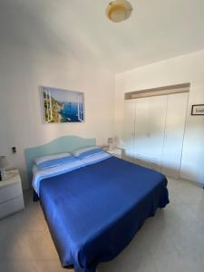 a bedroom with a blue bed in a white room at Bambiniello in Anacapri