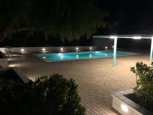 una piscina notturna illuminata con illuminazione Upescriptionsenalsenallsenalenalenale di Terre Iblee Resort a Chiaramonte Gulfi
