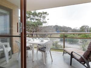 - Balcón con mesa blanca y sillas en Intrepid 13 fantastic unit with stunning water views, en Nelson Bay