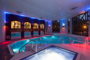 a swimming pool in a building with a tub at Crowne Plaza Gerrards Cross by IHG in Beaconsfield