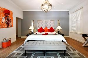 a bedroom with a large white bed with red pillows at La Providence in Franschhoek
