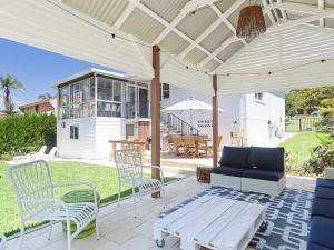 une terrasse avec un canapé, une table et des chaises dans l'établissement Little Beach House Little Beach with air con WiFi and boat parking, à Nelson Bay
