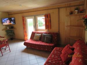 ein Wohnzimmer mit einem roten Sofa und einem Fenster in der Unterkunft Gruppenbungalow-Waldhaus-Am Ferienpark in Mirow