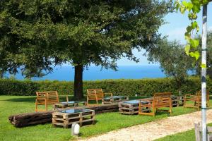 a group of wooden benches and tables under a tree at Casale del Mare in Castiglioncello