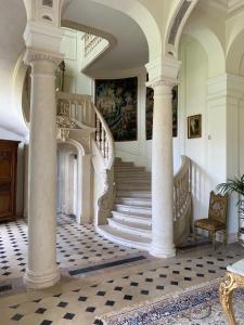a large room with white columns and a staircase at Château du Maurier in La Fontaine-Saint-Martin