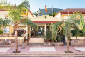 
a large building with palm trees in front of it at Residencial El Llano in Valle Gran Rey
