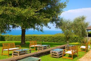 a group of tables and chairs under a tree at Casale del Mare in Castiglioncello