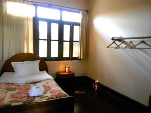 ein Schlafzimmer mit einem Bett mit einem Fenster und einem Bett sidx sidx sidx in der Unterkunft Manichan Guesthouse in Luang Prabang