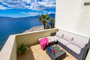 a balcony with a couch and a view of the ocean at Apartments Villa Nora in Rijeka