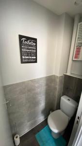 a bathroom with a toilet and a sign on the wall at Lyloo Studio Epernay in Épernay