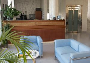 a lobby with two blue chairs and a counter at Hotel Aurora in Porto Cesareo