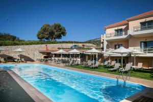 a pool at a hotel with chairs and umbrellas at Crystal Palace - Vista in Skala