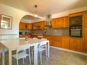 una cocina con armarios de madera y una mesa y sillas blancas. en Maison de Village Atypique 8-10 pers, en Saint-Gervasy