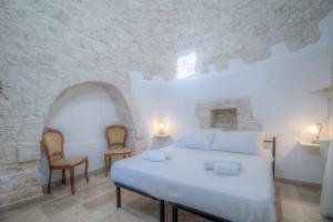 a bedroom with a white bed and two chairs at Trulli La Piazzetta by Rentbeat in Cocolicchio +34 photos