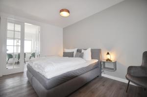 een witte slaapkamer met een bed en een stoel bij Schipperhus in Timmendorfer Strand