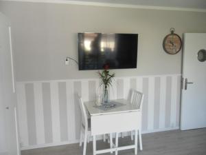a white table and chairs with a tv on the wall at Seemannskiste in Grömitz
