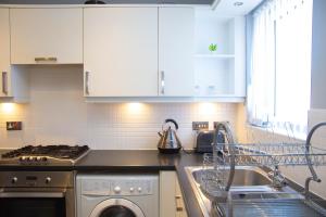 a kitchen with white cabinets and a washing machine at Romulus Court Fenham in Elswick