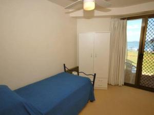 a bedroom with a blue bed and a window at Harbourside 5 ground floor waterfront unit in Soldiers Point