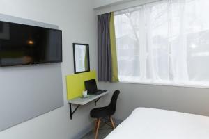 a room with a bed and a desk with a laptop at Harben House in Milton Keynes