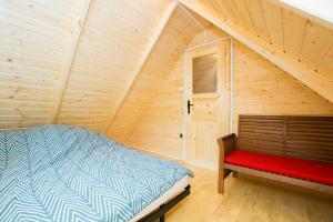 a bedroom with a bed and a red bench at Domki KARO in Rowy
