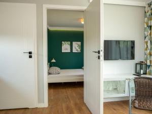 1 dormitorio con pared de acento verde y puerta corredera en Hostel w ogrodzie, en Grudziądz