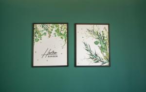 twee ingelijste foto's van planten op een groene muur bij Hostel w ogrodzie in Grudziądz