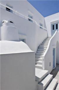 - un bâtiment blanc avec des escaliers et une porte bleue dans l'établissement Casa Florina, à Imerovigli