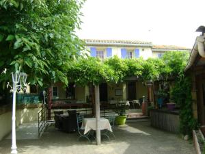 einen Tisch und einen Baum vor einem Haus in der Unterkunft Le H de SERNHAC in Sernhac