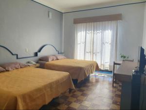 a hotel room with two beds and a window at Hotel Rivera in Oaxaca City
