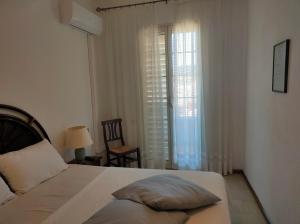 ヴィッラシミーウスにあるAppartamenti & Rooms Mariaのベッドルーム1室(ベッド1台、椅子、窓付)