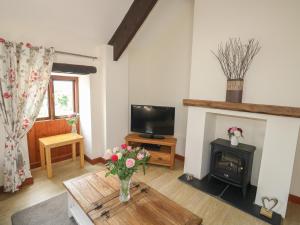 a living room with a fireplace and a vase of flowers at The Hayloft in Liskeard