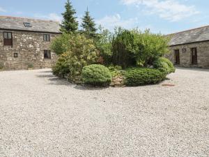 a stone building with bushes in front of a yard at The Hayloft in Liskeard