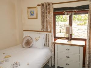 1 dormitorio con cama, ventana y vestidor en The Hayloft, en Liskeard