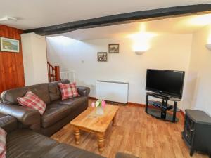 a living room with a couch and a tv at The Stable in Bude