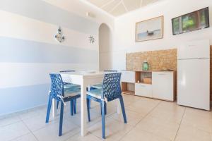 een keuken met een tafel, stoelen en een koelkast bij Le Gioie - Dimora Scalelle - Villetta con giardino e veranda vista mare in Torre Vado