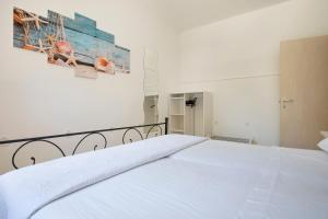een wit bed in een slaapkamer met een schilderij aan de muur bij Le Gioie - Dimora Scalelle - Villetta con giardino e veranda vista mare in Torre Vado
