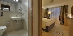 a bathroom with a bed and a sink and a toilet at Apollo Hotel Bratislava in Bratislava