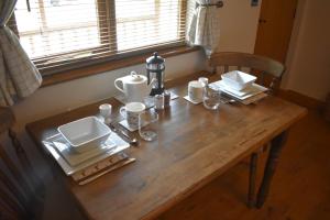 a wooden table with plates and dishes on it at Lyonshall Lodge in Kington