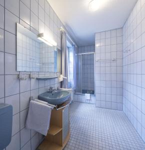 a white tiled bathroom with a sink and a toilet at Hotel zur Post in Mülheim an der Mosel