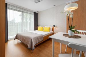 Un dormitorio con una cama con almohadas amarillas y una mesa. en Apartamenty Paliki en Jastrzębia Góra