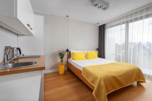 sypialnia z łóżkiem z żółtymi poduszkami i umywalką w obiekcie Apartamenty Paliki w Jastrzębiej Górze