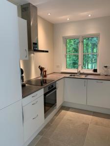 a kitchen with white cabinets and a sink and two windows at Langø Feriecenter - Garden View in Nakskov