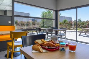 a table with a plate of food and bread and drinks at B&B HOTEL Perpignan Saleilles in Perpignan