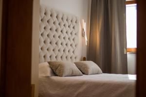 een slaapkamer met een groot bed met een wit gewatteerd hoofdeinde bij Apartmani VILLA KALINIC in Njivice