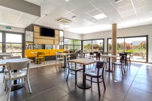 a dining room with tables and chairs and windows at B&B HOTEL Perpignan Saleilles in Perpignan