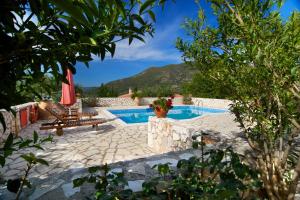 a patio with a pool and a table and a umbrella at VILLA KOUTSOYPIA STONE HOUSE in Sami