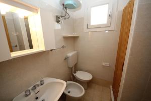 een badkamer met een wastafel, een toilet en een raam bij Arianna 01 in Rosolina Mare