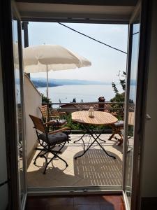 een patio met een tafel en stoelen en een parasol bij New cosy apartments with private parking in Opatija