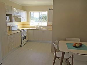 a kitchen with a table and a table and chairs at 15 'Kanangra', 39 Soldiers Point Road - fantastic unit right on the water in Soldiers Point
