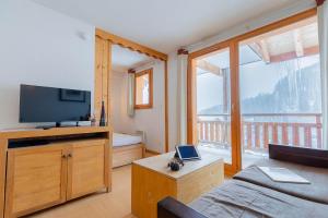 a living room with a television and a balcony at Madame Vacances Résidence Le Parc Des Airelles in Les Orres